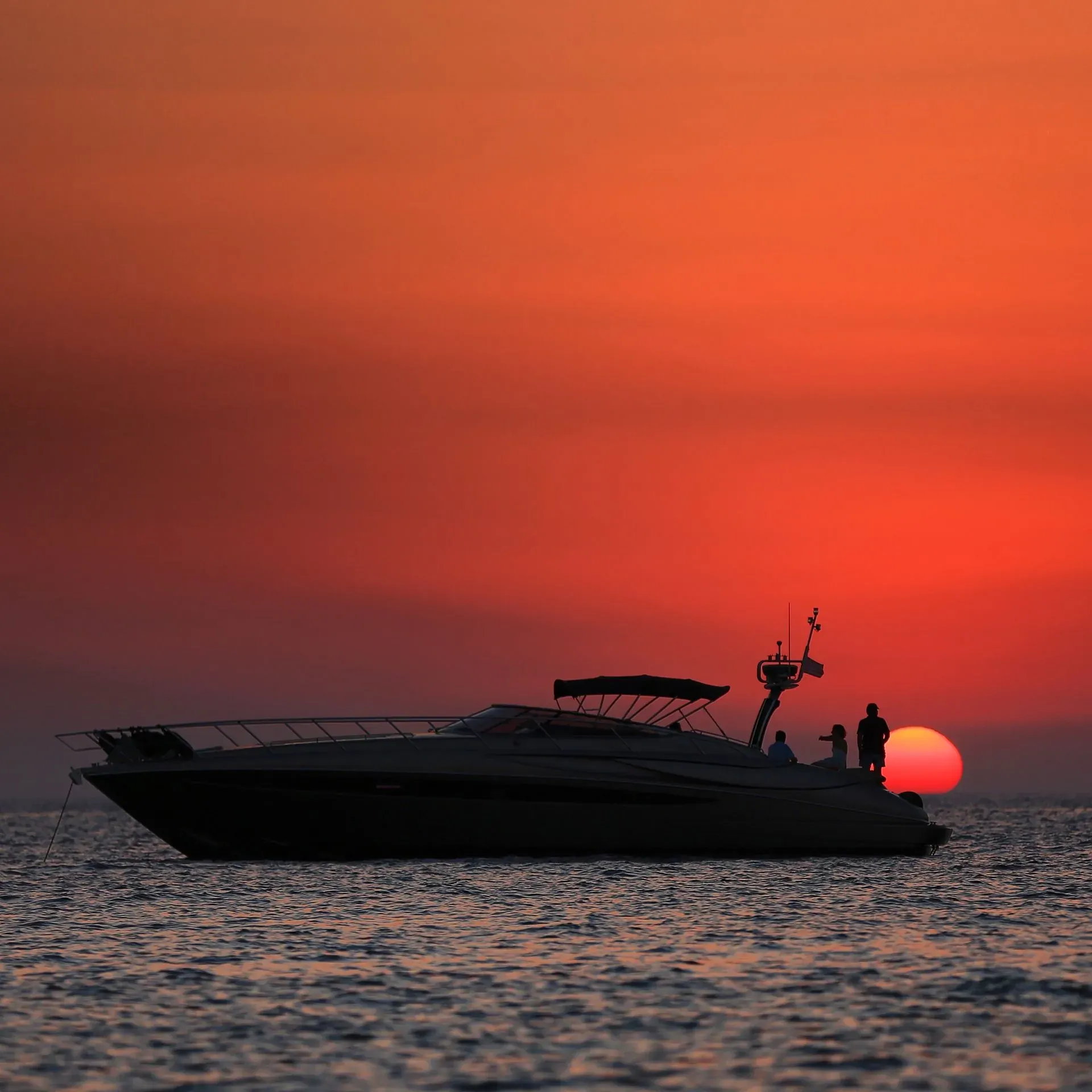 Lancha navegando ao pôr do sol vermelho