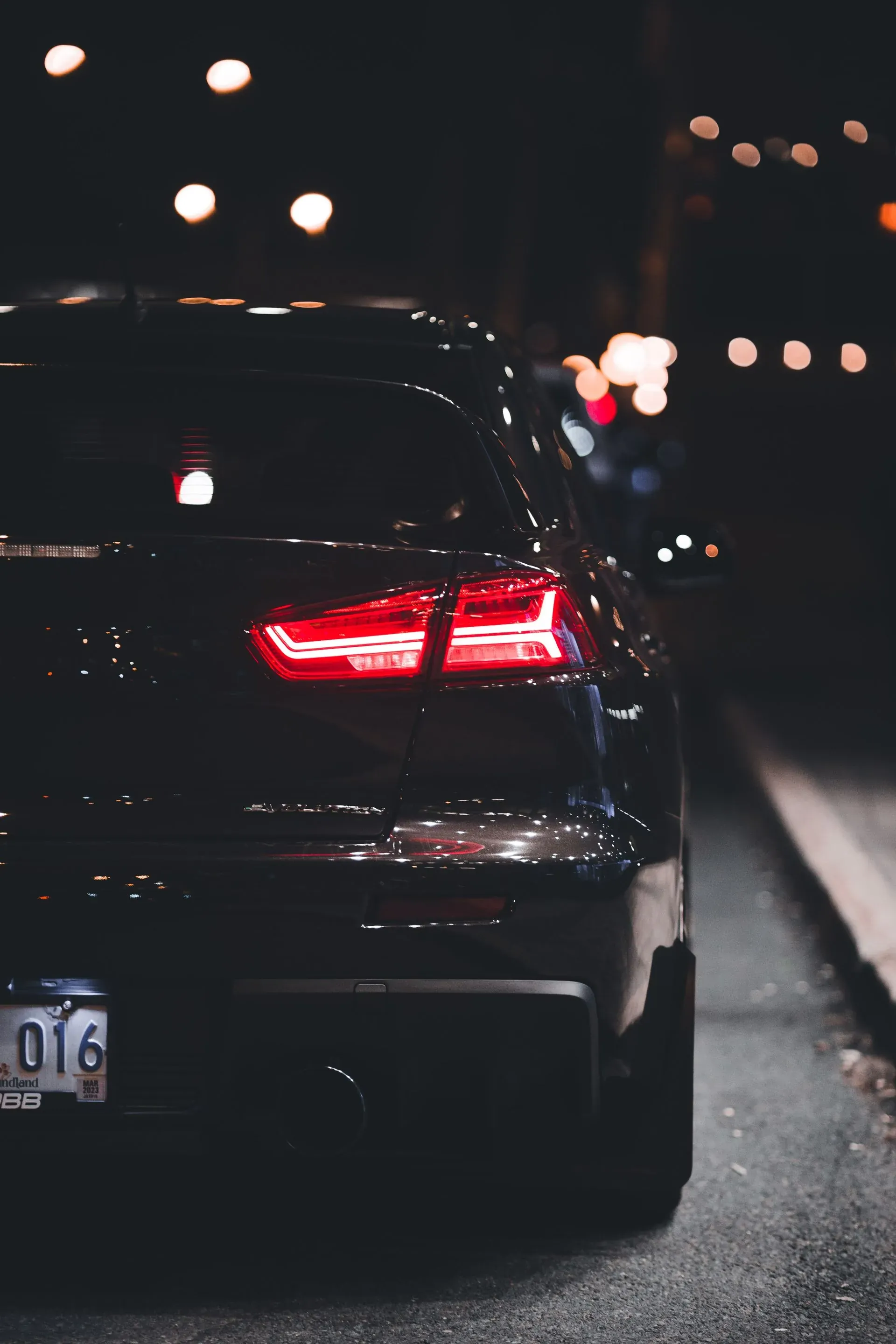 Carro preto à noite com lanternas acesas